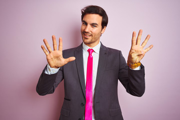 Sticker - Young handsome businessman wearing suit and tie standing over isolated pink background showing and pointing up with fingers number nine while smiling confident and happy.