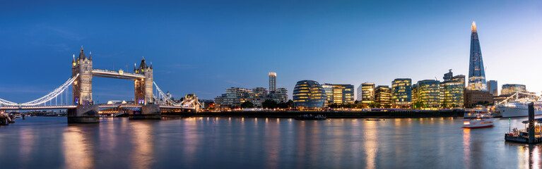 Fototapete - Die beleuchtete Skyline von London am Abend mit Tower Bridge und modernen Bürogebäuden, Großbritannien