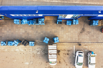 Wall Mural - Aerial view of freight warehouse of drinking water plant or factory, racks with plastic bottles or gallons ready for loading at trucks