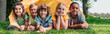 © LIGHTFIELD STUDIOS - panoramic shot of happy multicultural kids smiling while lying near camp