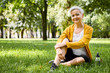 © Anatoliy Karlyuk - Happy energetic senior gray haired female relaxing on lawn sitting comfortably, smiling, going to have breakfast after training in city park. Age, retirement, active lifestyle and wellness
