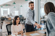 © mavoimages - Smiling young businessman shaking hands with an office colleague
