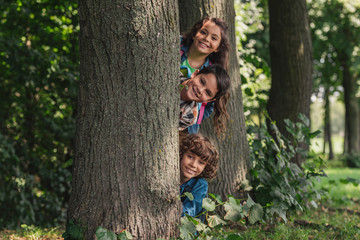 Wall Mural - happy boys smiling near tree trunk with adorable friend