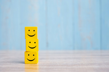 smile face on yellow wood cube. service rating, ranking, customer review, satisfaction and emotion c