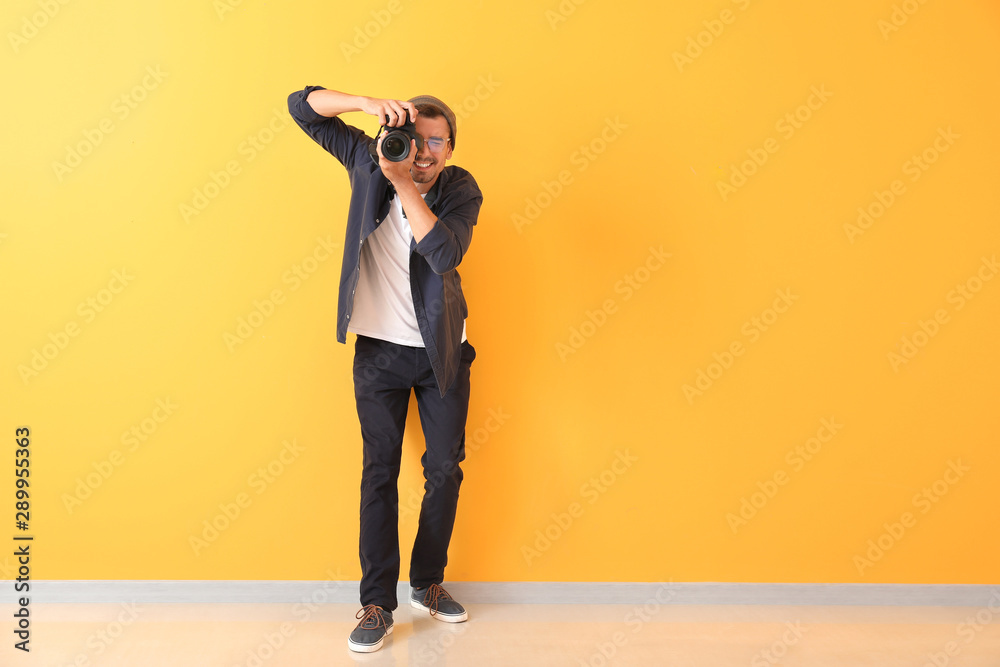 Young male photographer near color wall
