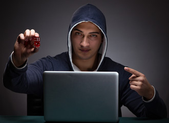 Wall Mural - Young man wearing a hoodie sitting in front of a laptop computer