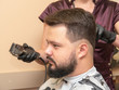 © eriksvoboda - Hair cutting in barbershop, close up view. Stylist cutting hair with clipper and black comb. Masters hands in black rubber gloves. Selective soft focus. Blurred background