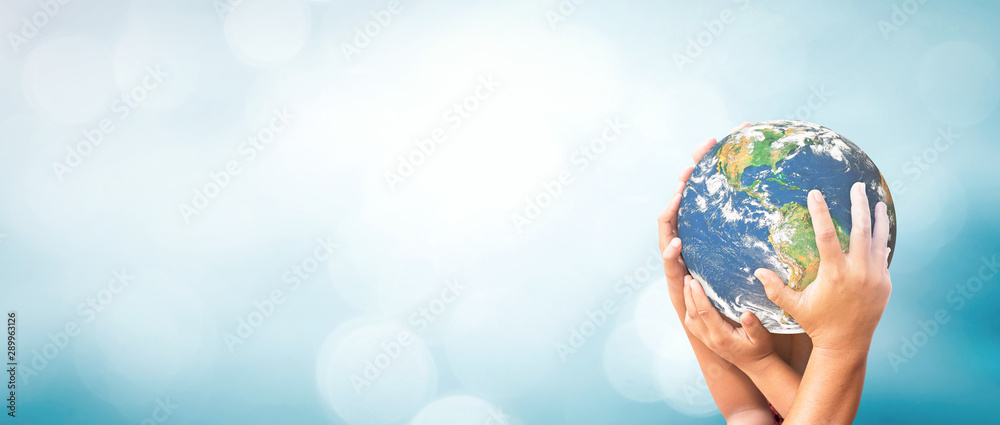World environment day concept: Earth globe in family hands over blurred nature background. Elements of this image furnished by NASA - obrazy, fototapety, plakaty 