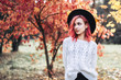 © bedya - Pretty girl with red hair and hat walking in the park, autumn time.