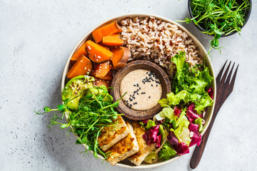 Wall Mural - Buddha bowl with tofu, avocado, rice, seedlings, sweet potato and tahini dressing.