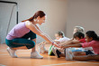 © zinkevych - PE teacher wearing leggings smiling while helping girl stretching