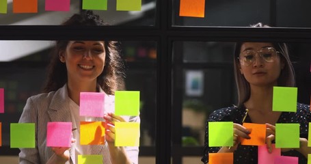 Wall Mural - happy diverse female colleagues talking working with sticky notes