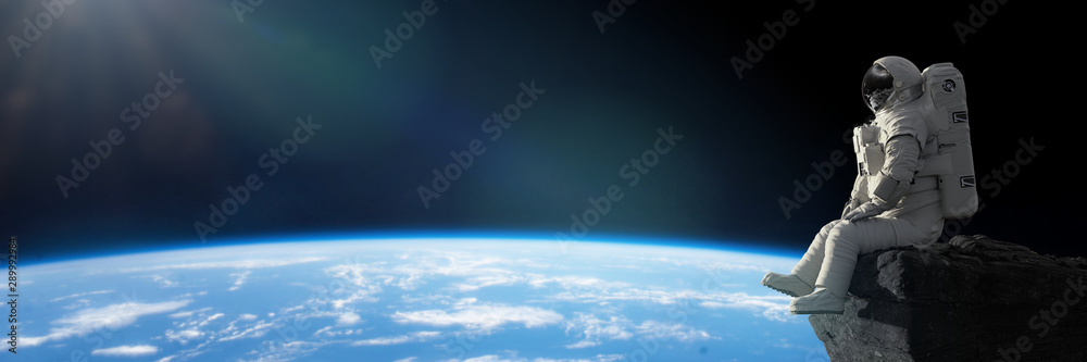 astronaut sitting on a cliff on the Moon in front of planet Earth  - obrazy, fototapety, plakaty 