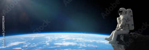 Fotografía astronaut sitting on a cliff on the Moon in front of planet Earth