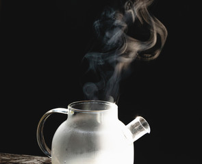 Wall Mural - The steam from a cup or pot of coffee or tea on the old wood table and black background, Warm drinks make good healthy, Selective focus.