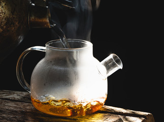 Wall Mural - The steam from a cup or pot of coffee or tea on the old wood table and black background, Warm drinks make good healthy, Selective focus.