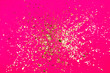 Golden flying sparkles on Plastic pink neon background. Festive backdrop for your projects.