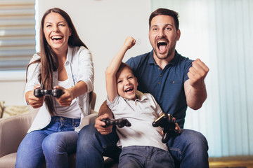 Wall Mural - Smiling family sitting on the couch together playing video games