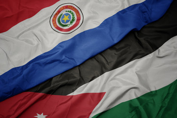 waving colorful flag of jordan and national flag of paraguay.