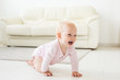 Smiling crawling baby girl at home on floor