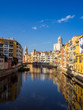 Girona's tipical skyline cityscape over the Onyar River with colourful river houses on a blue sunny sky, Church of Sant Feliu Cathedral landmark on background