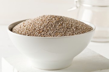 Wall Mural - Whole, organic white chia seeds heap in white bowl on white table background