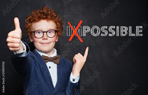 Valokuva Happy smart child pointing at possible inscription on chalkboard background