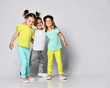 © FAB.1 - Studio portrait of children on a light background: full body shot of three children in bright clothes, two girls and one boy. Triplets, brother and sisters.