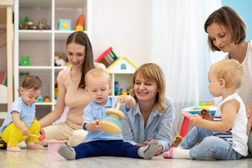 Group of happy moms with their babies in nursery. Preparing children for kindergarten