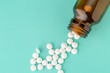 White round tablets scattered near glass bottle of pills
