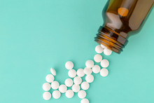 White Round Tablets Scattered Near Glass Bottle Of Pills