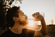 Man drinking water from the plastic bottle in the sunset