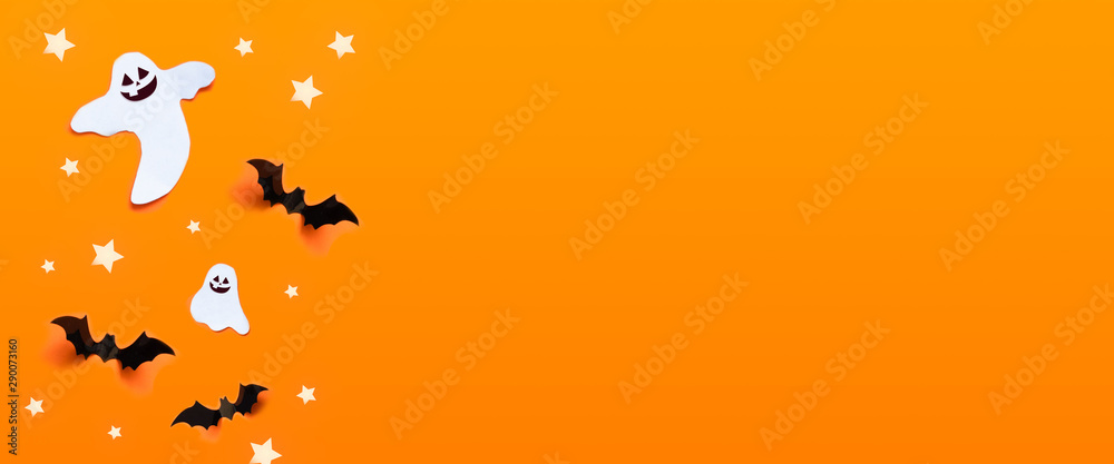 Autumn holiday composition. Halloween celebration concept with bats, ghost, spider web, stars over a orange background.