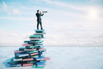 Career growth and development concept with businessman on book mountain looking through a telescope.