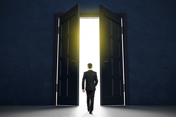 Aufkleber - New life beginning concept with businessman entering open black doors in abstract bright space.