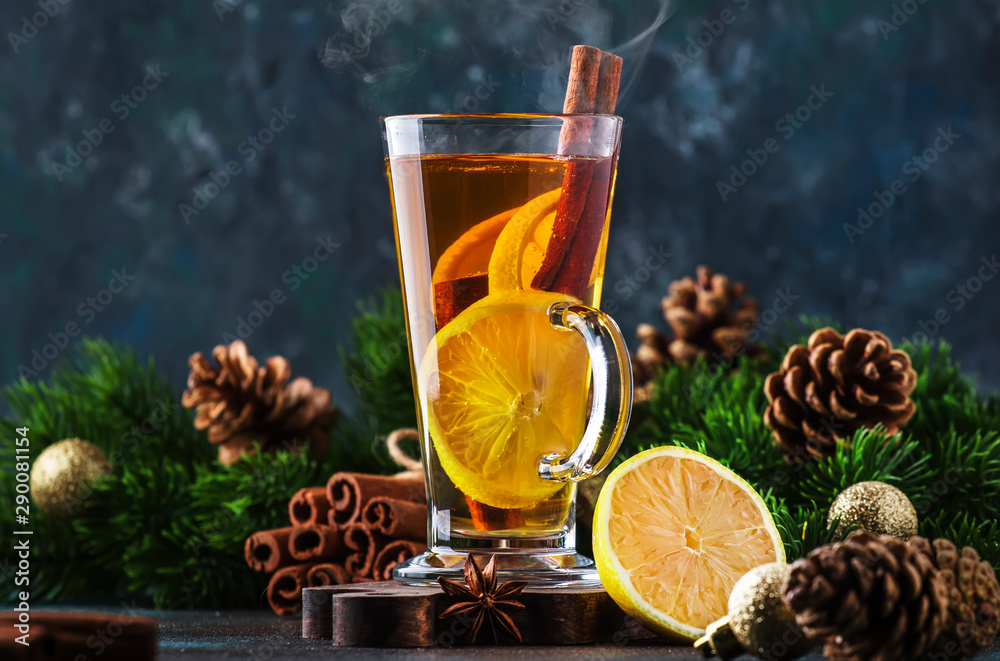 Christmas or New Year hot winter drink, spicy grog cocktail, sangria or mulled wine with tea, lemon, rum, cinnamon, anise. Rustic style, copy space - obrazy, fototapety, plakaty 