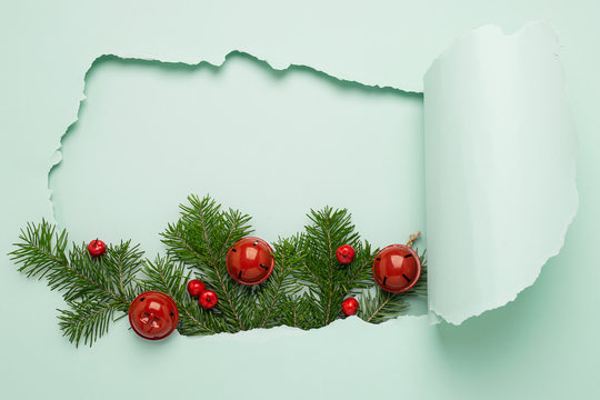 New Year or Christmas layout and a big hole on a paper background mint color. Christmas tree branch toys on a blue bright background. New Year or Christmas concept. Flat layout.