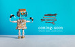 Web site under construction Coming Soon template page. Toy robot looks at a set of hand wrenches for maintenance repairs and service works. Blue wall and copy space on gray background.