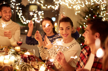 Poster - winter holidays and people concept - happy friends with sparklers celebrating christmas at home feast