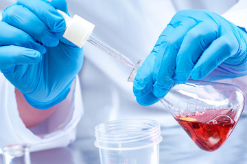 Poster - hands in blue gloves holding a test tube. hands of the laborant close-up. conducting experiments wit