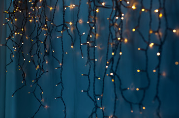 Wall Mural - holiday, illumination and decoration concept - bokeh of christmas garland lights over dark blue back