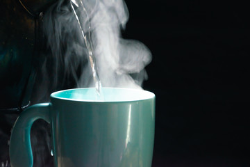 Wall Mural - The steam from a cup of coffee or tea on the old wood table and black background, Warm drinks make good healthy, Selective focus.