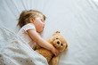 © kaloriya - Little baby sleeping on bed embracing soft toy, free space