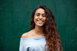 © mimagephotos - front portrait of happy young Indian woman laughing against green background