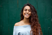 Front Portrait Of Happy Young Indian Woman Laughing Against Green Background