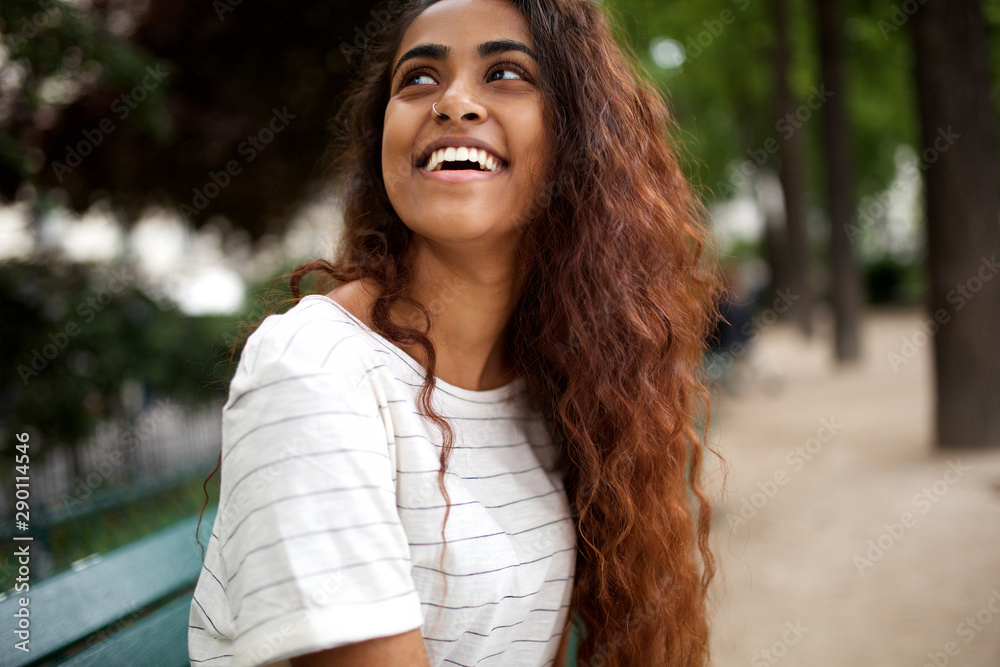 beautiful young indian woman laughing in park - obrazy, fototapety, plakaty 