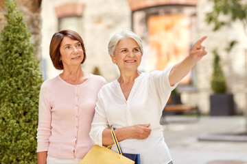 Canvas Print - sale, consumerism and people concept - two senior women or friends with shopping bags on tallinn city street