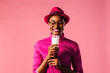 © Carlos David - Portrait of a young woman with glasses holding and drinking a glass of milk, looking down, isolated on pink studio background.
