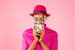 © Carlos David - Portrait of a smart young woman with glasses drinking a coffee mug and looking to side, isolated on pink studio background.