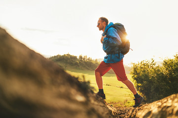 Wall Mural - backpacker traveler in trekking boots jumping over the ditch on mountain dirty path at summertime su